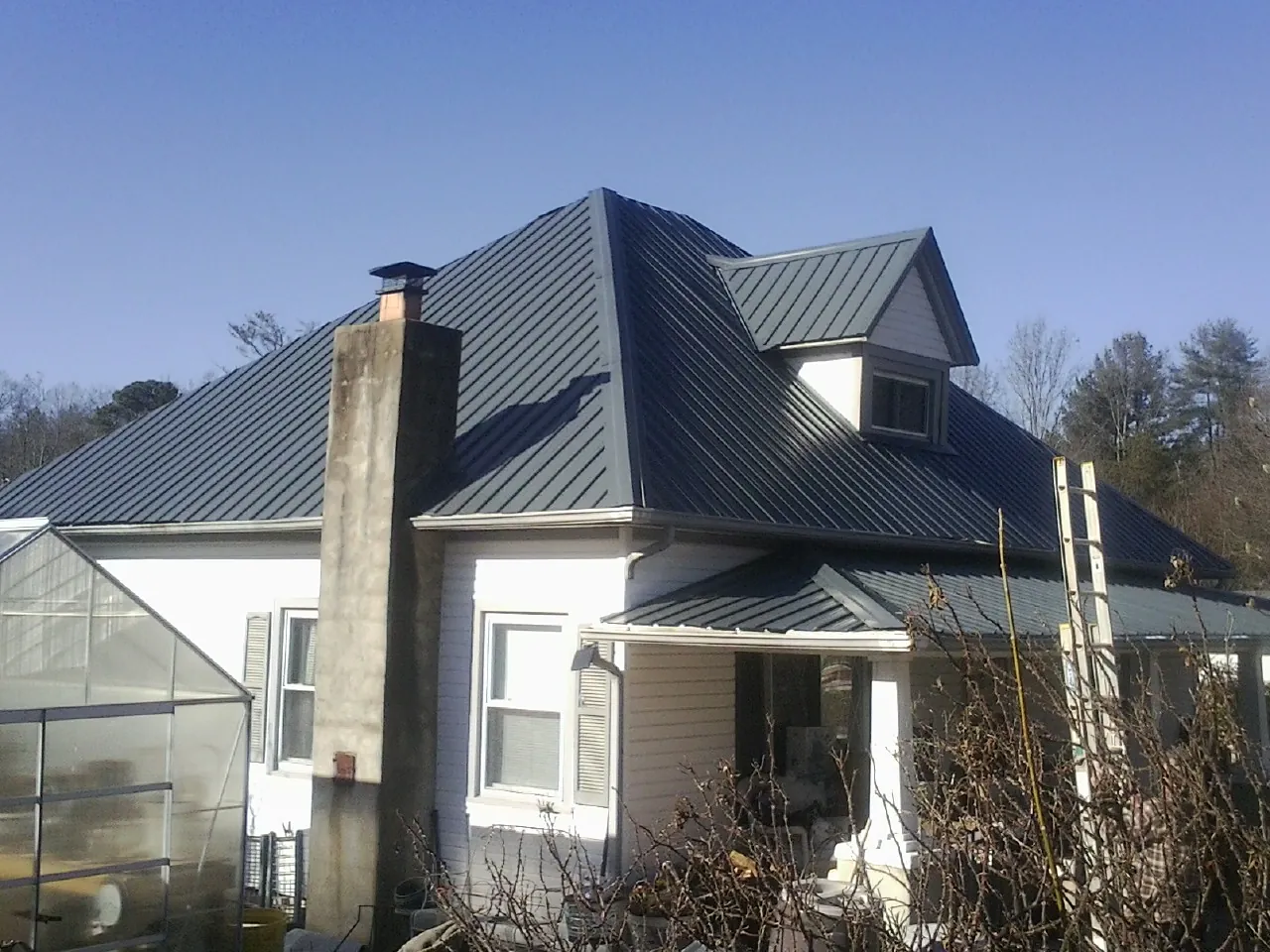 Dark blue standing seam metal roof on a white farmhouse with dormer — Slate & Tile Roof Repair by Roofing Brothers in Vermont