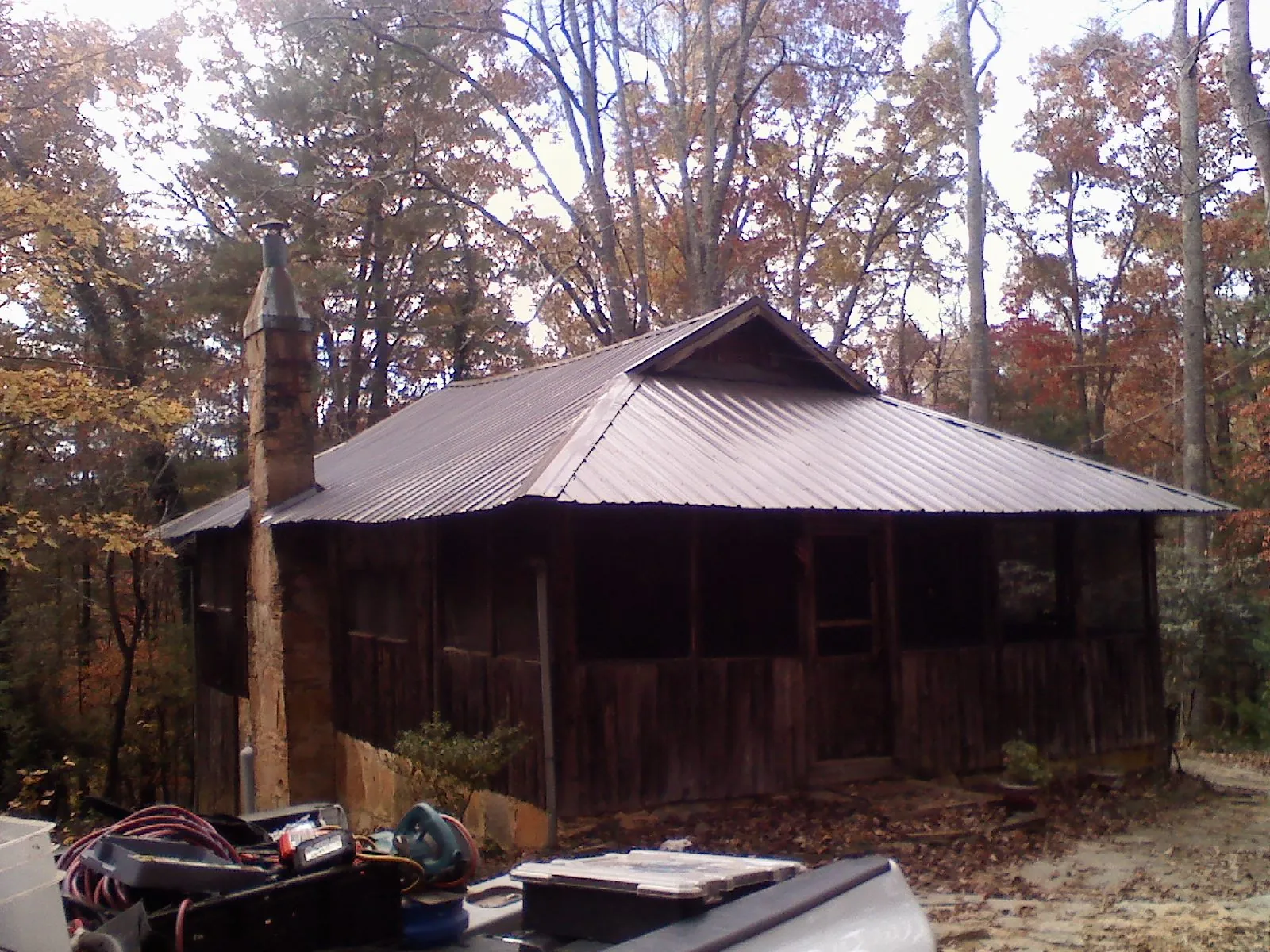 Brown metal hip roof on an old cabin with a stone chimney in Vermont
