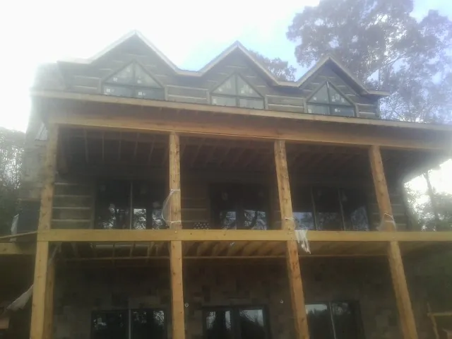 Dormers and porch framing on a large log home under construction — Roof Coating work by our crew in Vermont