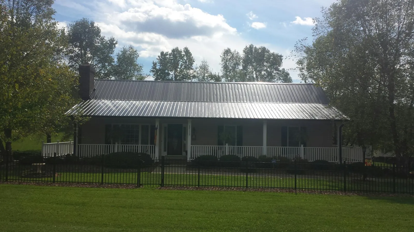 Gray metal roof on a brick ranch with a full width front porch — Gutter Guard Installation work by our crew in Vermont