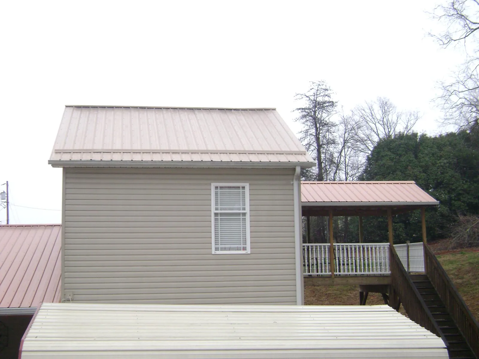 Tan metal roofs on a two story addition and attached porch, from a Roof Replacement job in Vermont
